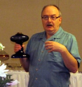 Roger Lash web - The Village Reporter Roger Lash, guest speaker, explaining the usual blue colored oil based lamp to the membership.