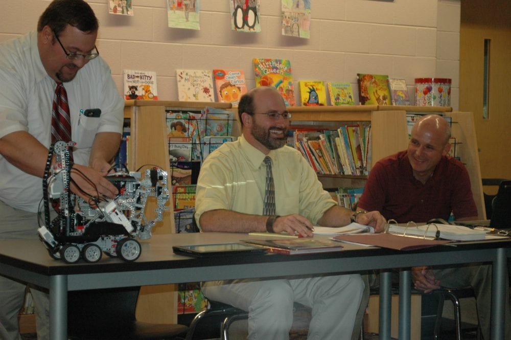 HS/MS Principal Roger Cade demonstrates a robotic elephant created by students at the recent school board meeting.