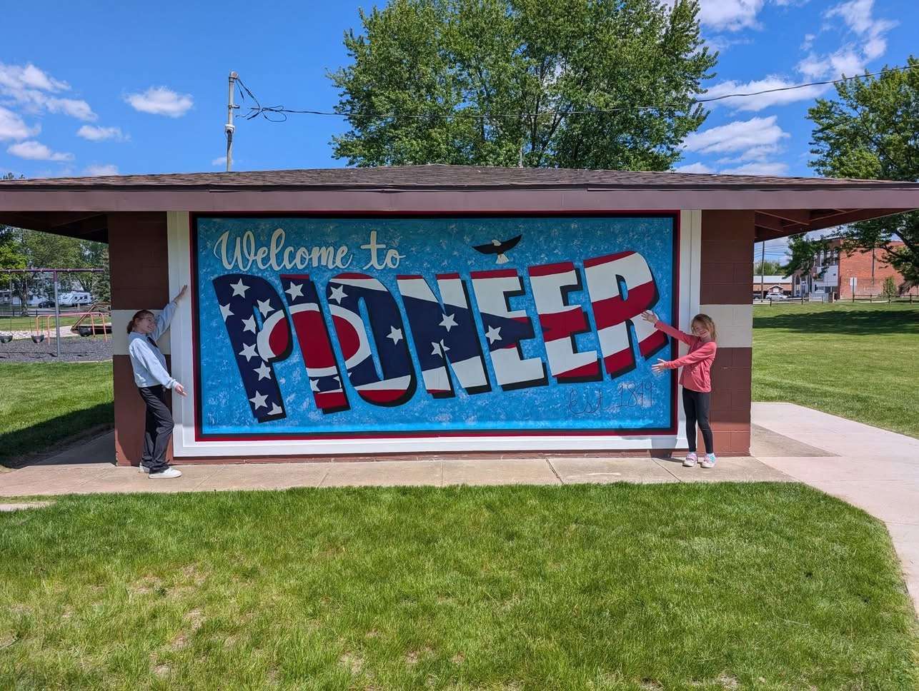 North Central Students Mary and Molly MacKinnon pose near the newest Pioneer Mural at Crommer Park