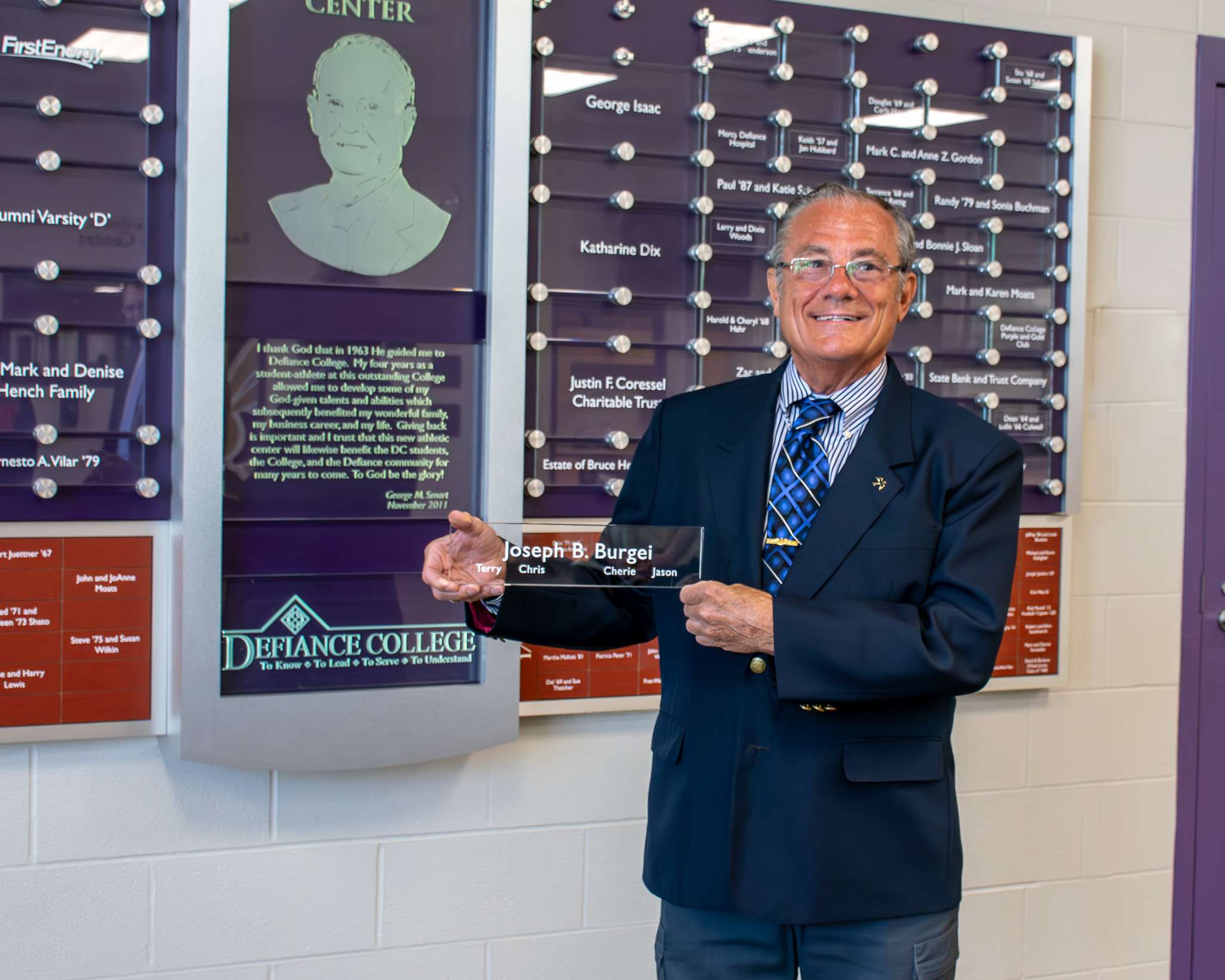 Joseph B. Burgei holding commemorative plate at Defiance College