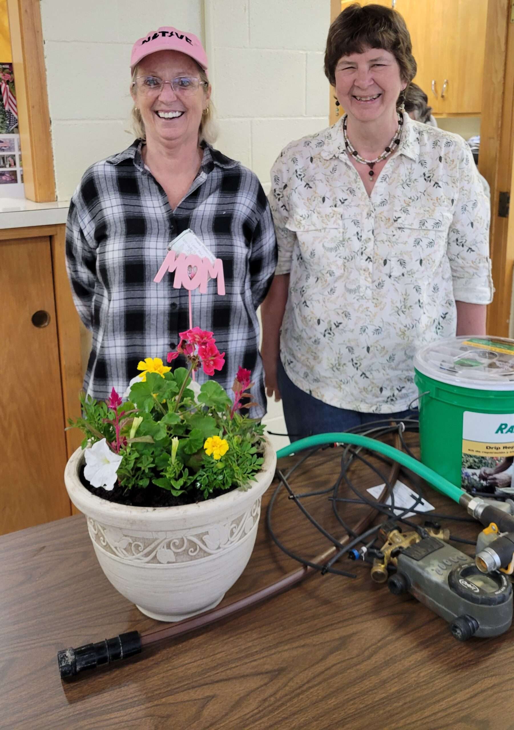 Rhonda Obus, left, with her Mother’s Day potted arrangement, and Rozetta Luke, right, with components from her garden irrigation system at the Pulaski Garden Club’s May 5, 2026 meeting.