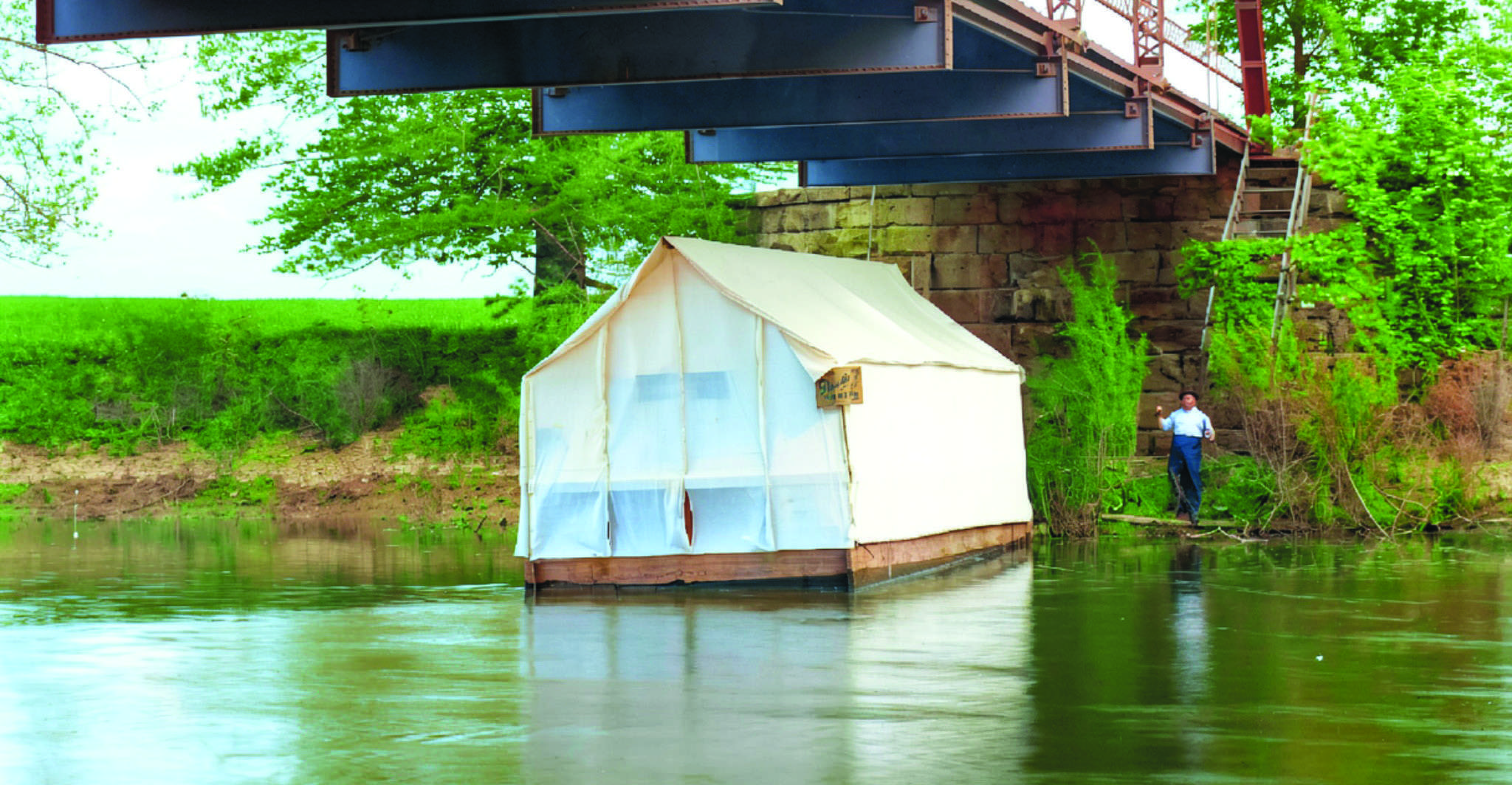 The Ark, a colorized 1909 image of the floating tavern on the St. Joseph River, anchored under the Clarksville bridge near Edgerton.