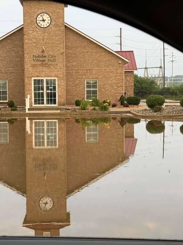 The Holiday City Village Hall is reflected in standing floodwater, July 17, 2026.