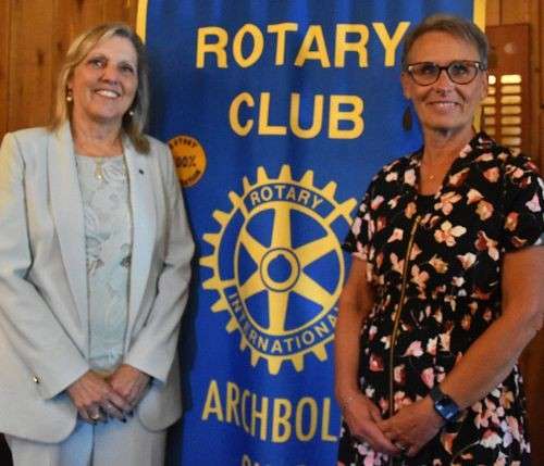 Two women smiling in front of the Archbold Rotary Club banner