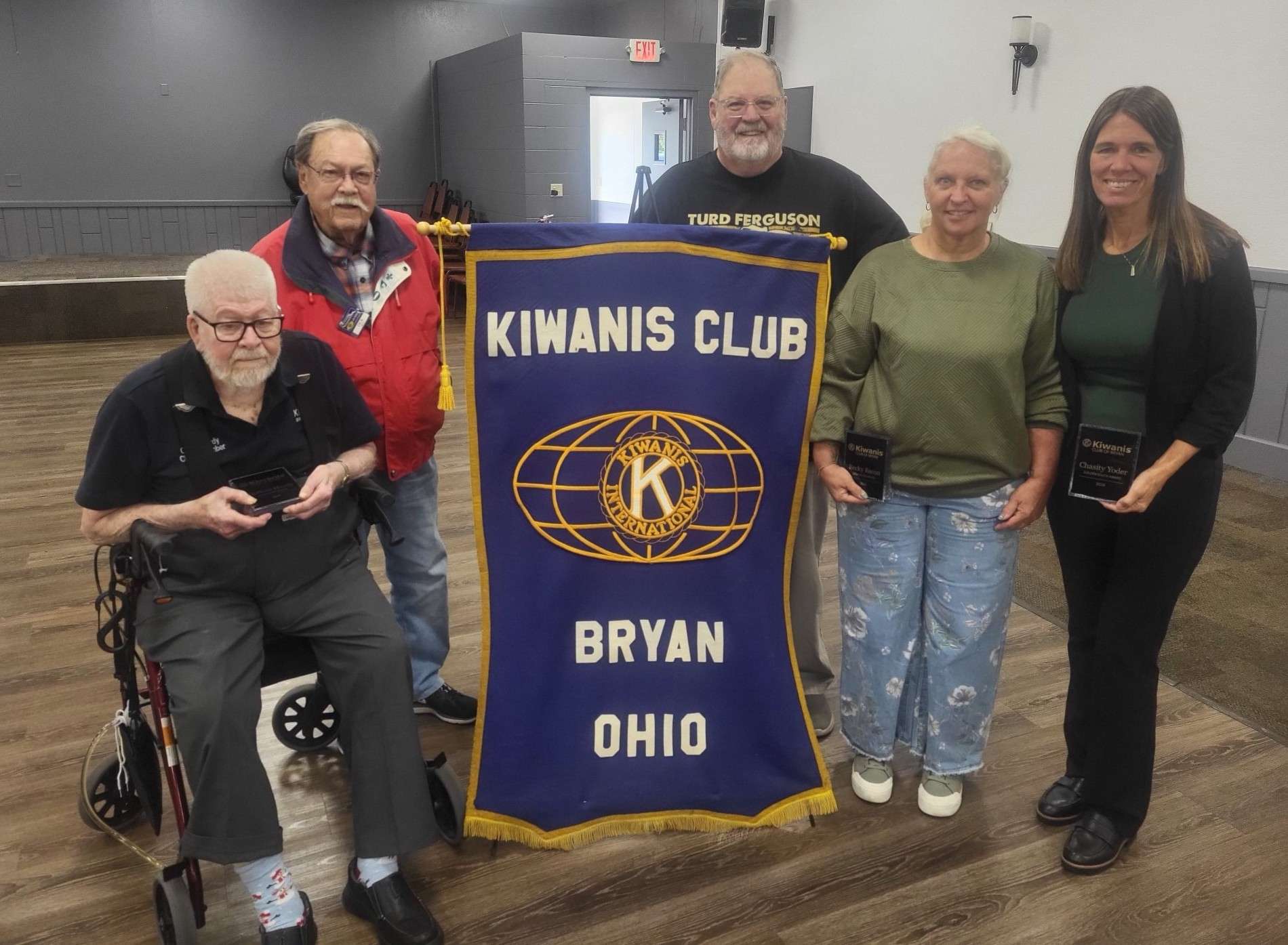 Five Kiwanis Club of Bryan members with award plaques beside the club banner