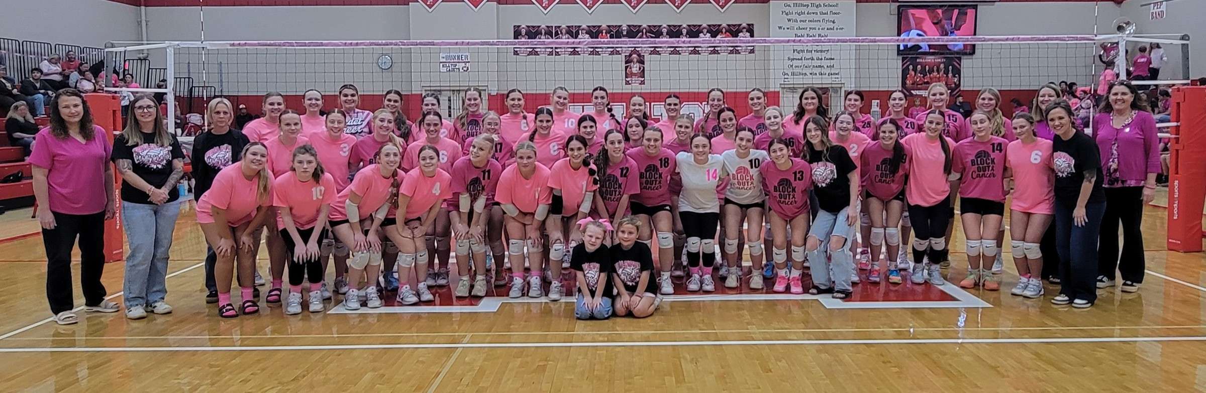 Hilltop and North Central volleyball players, coaches and two children in pink and black shirts in the Hilltop gym