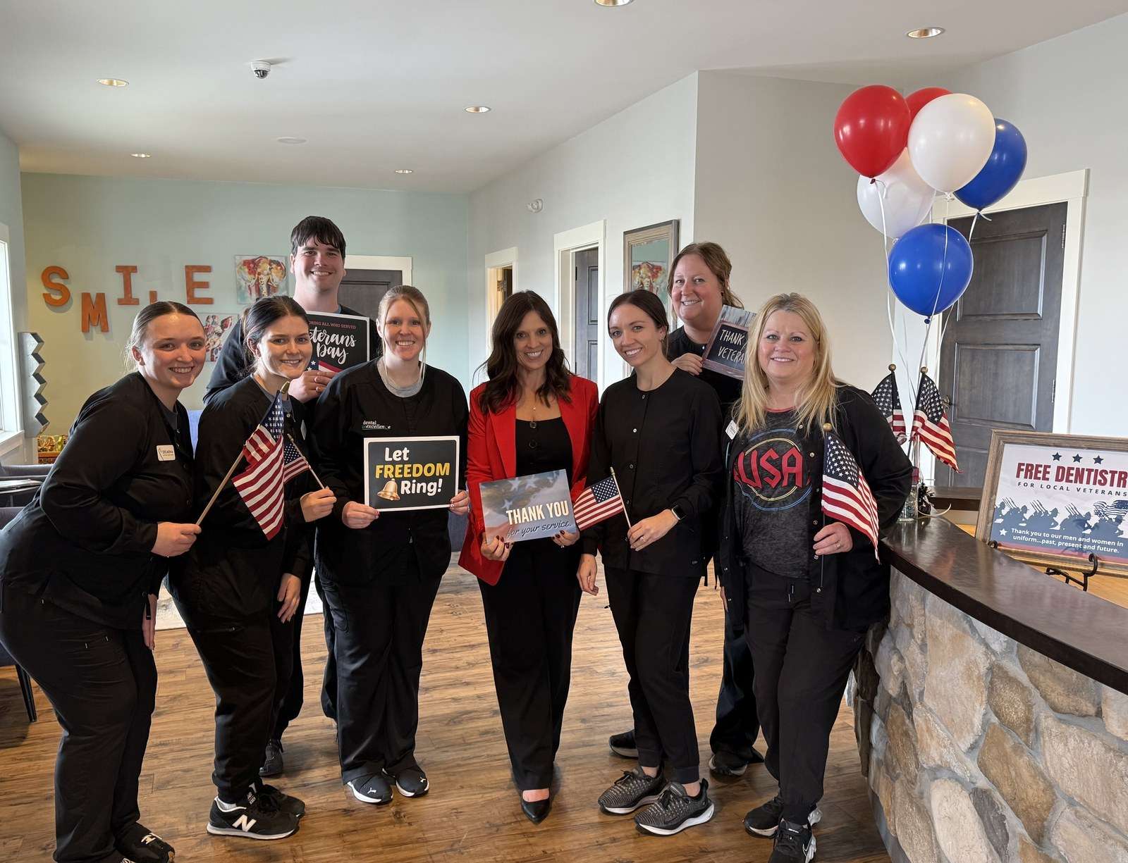 Dental Excellence staff holding flags and Veterans Day signs