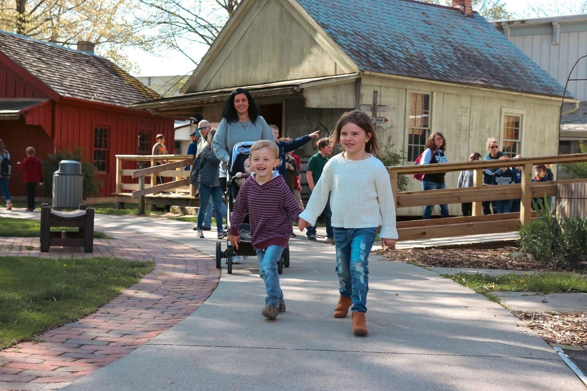 Two children walk along a path at Sauder Village
