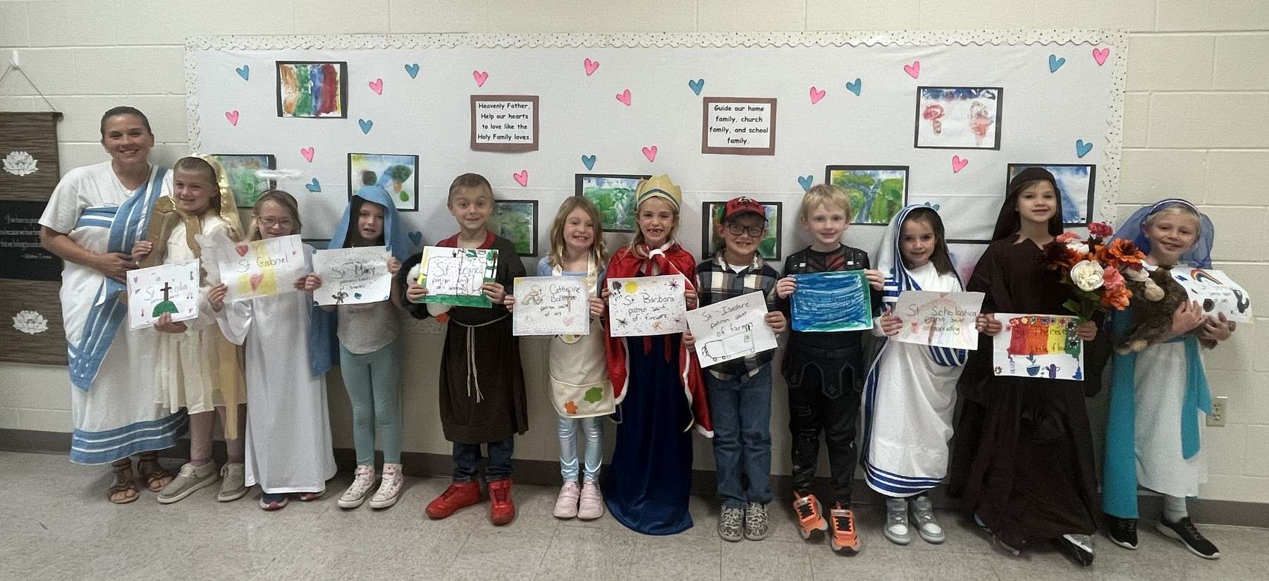 Second-grade students dressed as saints holding artwork at St. Mary School