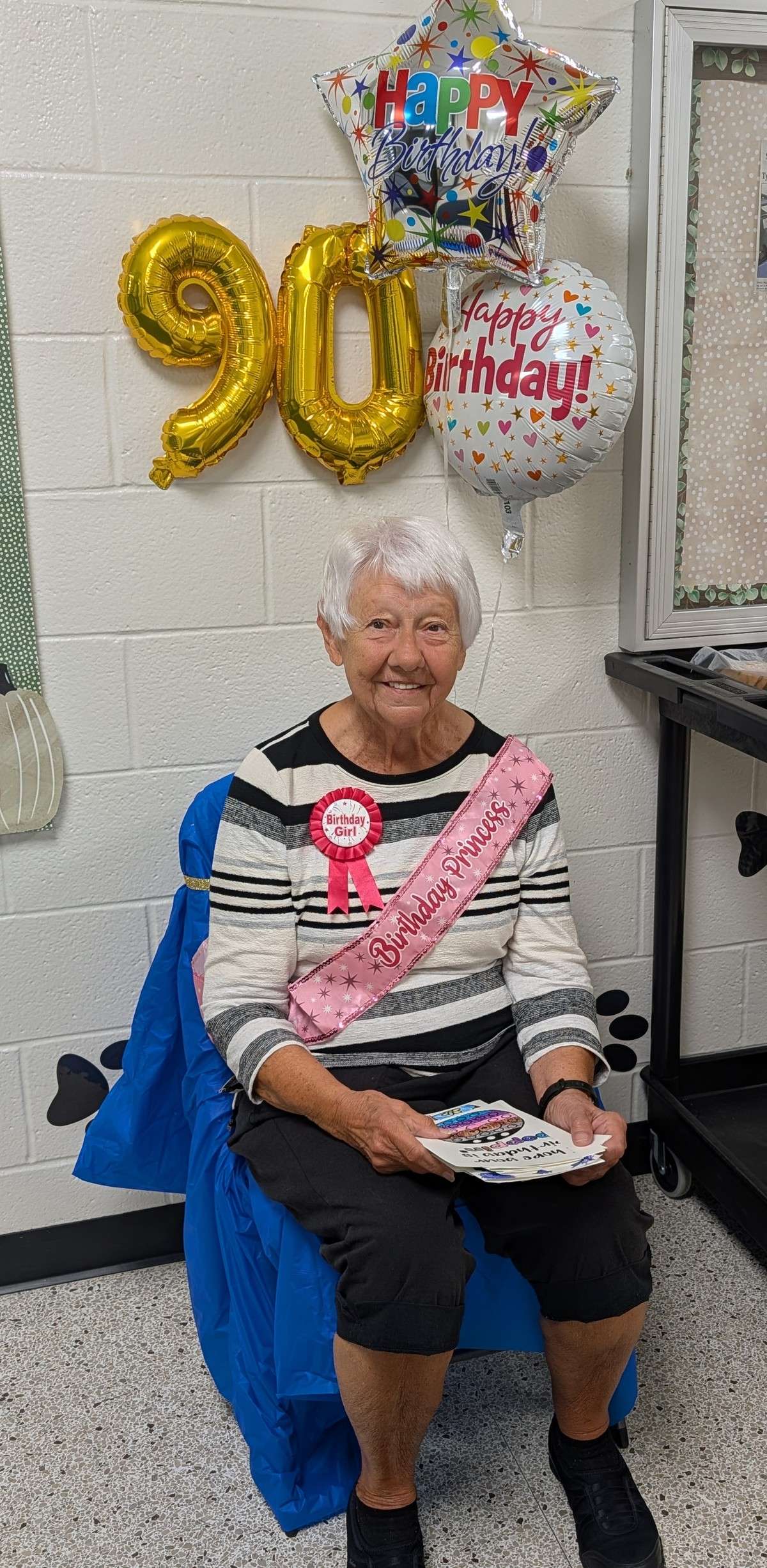 Marilyn Frank in a Birthday Princess sash under 90 balloons at Stryker Elementary