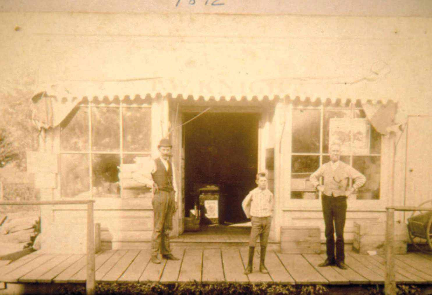 Earle Knight as a child standing with his father and Dr. Bassett in front of T.W. Knight Grocery in Swanton
