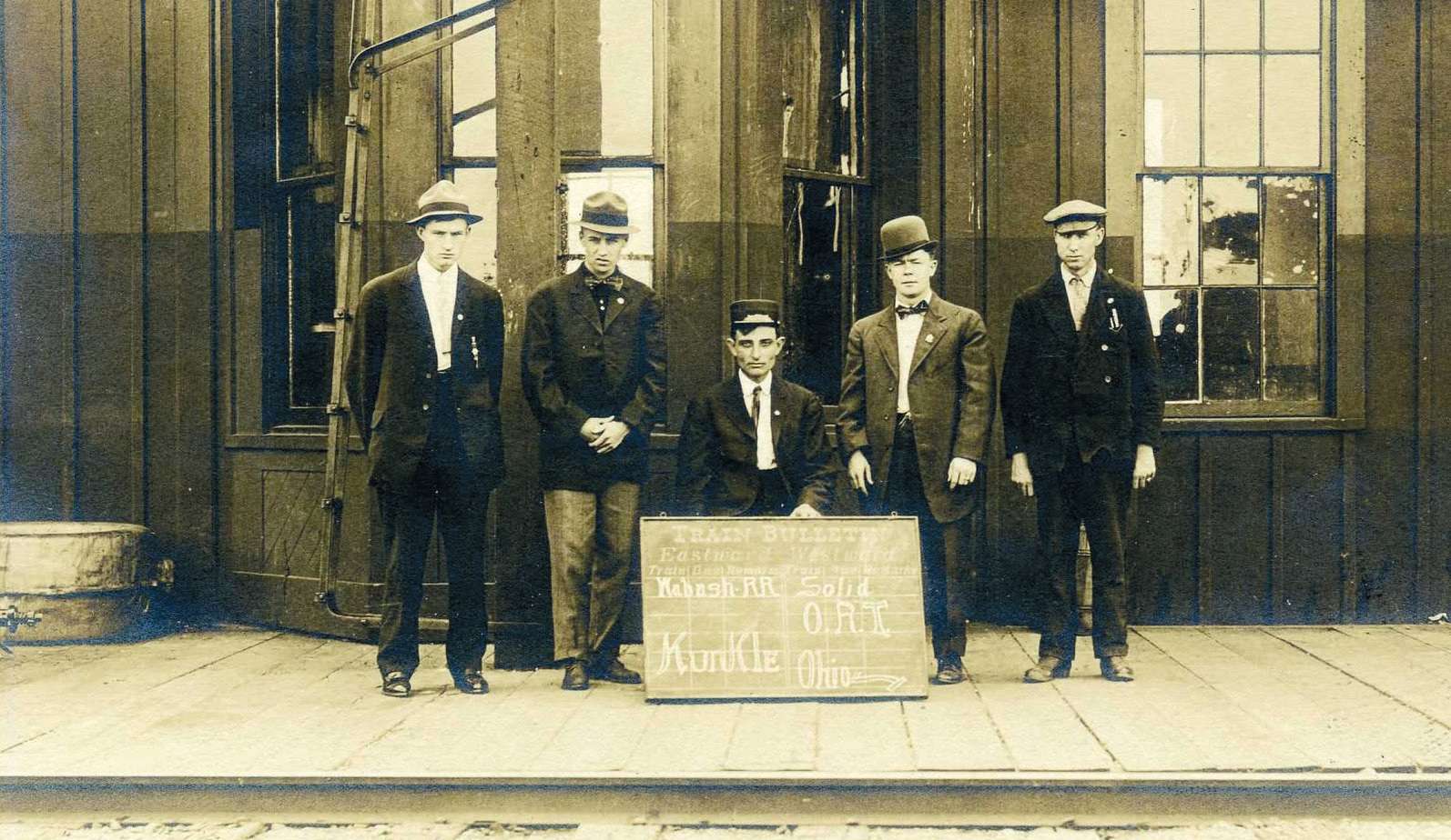 1909 Kunkle Wabash depot staff standing beside a Train Bulletin chalkboard